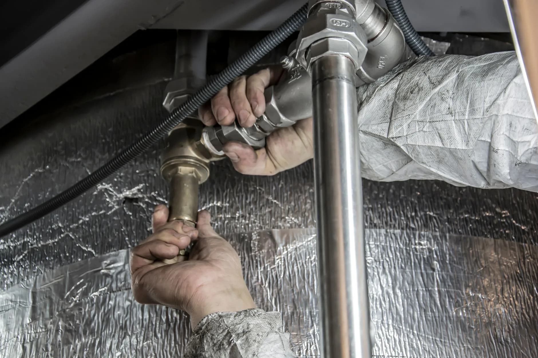 Plumber repairing a pipe under a sink